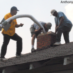 A crew installs a metal chimney liner into a masonry chimney.